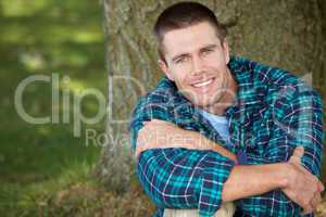 Man sitting against tree trunk