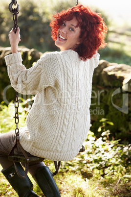Woman on country garden swing
