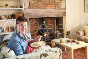 Young man eating meal by fire