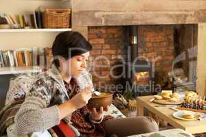 Young woman having tea by fire