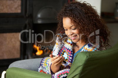 Young woman sitting by fire with phone