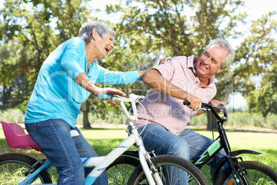 Senior couple playing on children's bikes