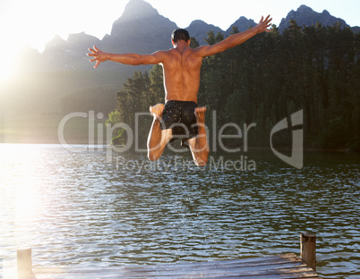 Young man jumping into lake