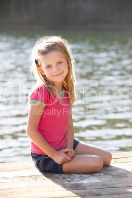 Young girl sitting by lake