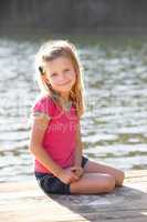 Young girl sitting by lake