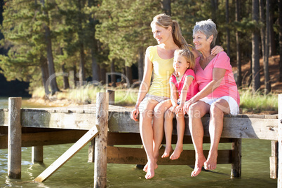 Mother,daughter and grandmother sitting by lake