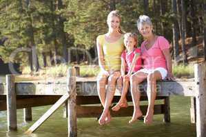 Mother,daughter and grandmother sitting by lake