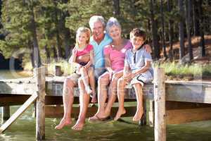 Senior couple sitting by lake with grandchildren