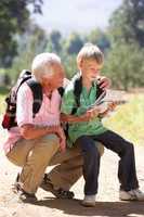 Senior man reading map with grandson on country walk