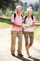 Senior couple reading map on country walk