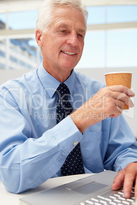 Senior businessman with laptop and coffee