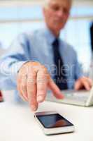 Senior businessman with laptop and phone