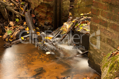 Waldbach mit zerfallenem Stauwehr