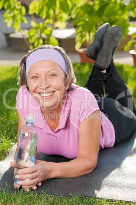 Senior sportive woman lying on mat sunny