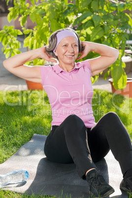 Senior sportive woman doing sit-ups sunny day