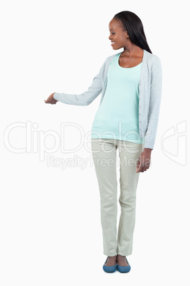 Smiling young woman pointing at something behind her Smiling young woman pointing at something behind her