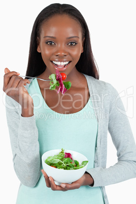 Smiling young woman eating salad