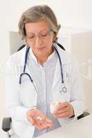 Medical doctor senior female hold pills office
