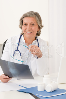 Senior doctor female sit behind office desk