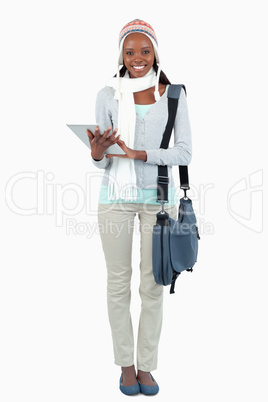 Smiling young student with scarf, hat and touchpad