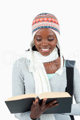 Close up of smiling student in winter clothes reading in her boo