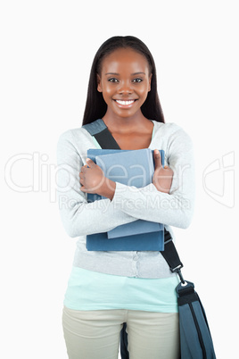 Smiling young female student with books and bag