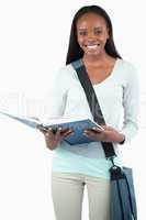 Smiling young student with bag reading in her book