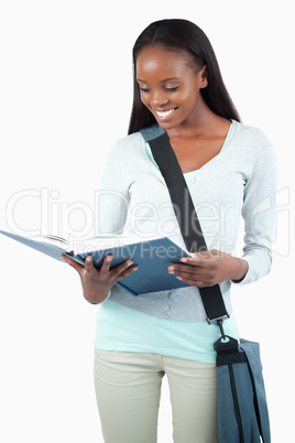 Smiling student with bag reading in her book