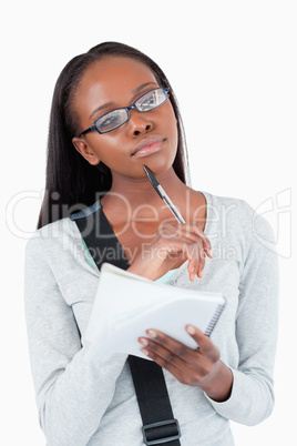 Young woman with notepad and glasses in thoughts