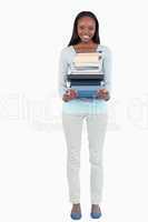 Smiling young woman carrying a stack of books