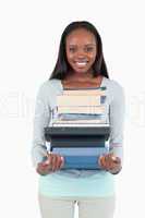 Smiling young woman with a pile of books