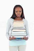 Sad looking young woman with stack of books