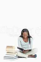 Young woman reading next to a pile of books