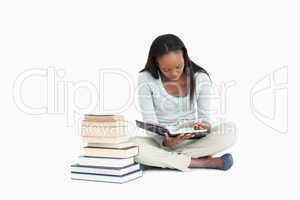 Young woman reading next to a stack of books