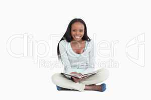 Smiling young woman sitting on the floor with a book