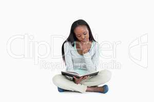 Young woman sitting on the floor reading in her book