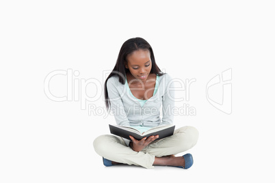 Young woman sitting cross-legged on the floor reading