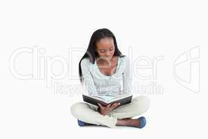Young woman sitting cross-legged on the floor reading
