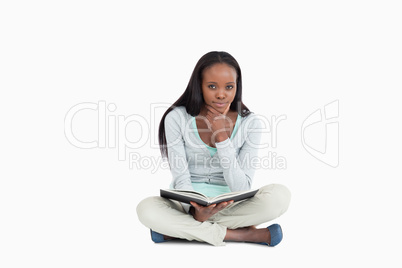 Young woman sitting on the floor thinking about her book