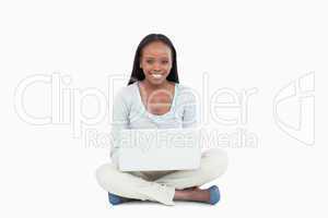 Smiling young woman sitting on the floor with her laptop