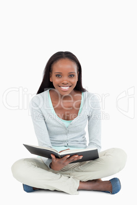 Smiling young woman on the floor with her book