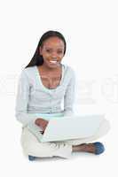 Smiling young woman with laptop on the floor