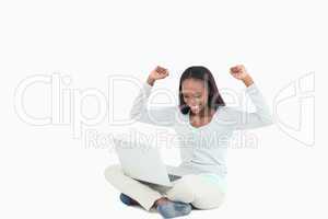 Young woman celebrating in front of her laptop