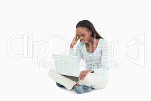 Woman sitting on the floor experiencing laptop problems
