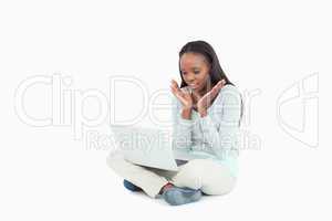 Woman sitting on the floor with laptop seeming curious