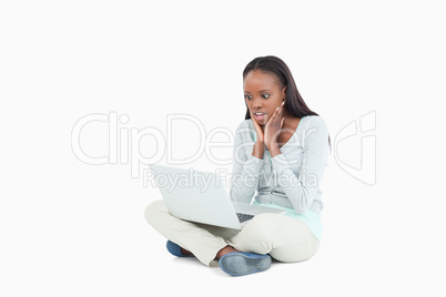 Young woman on the floor cannot believe whats on her screen