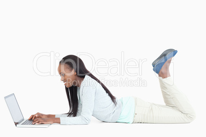 Side view of woman lying on the floor with her laptop