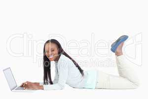 Side view of smiling woman lying on the floor with her laptop