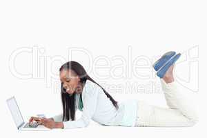 Side view of smiling woman lying on the floor working on her lap