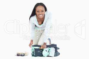 Young woman trying hard to get her suitcase closed